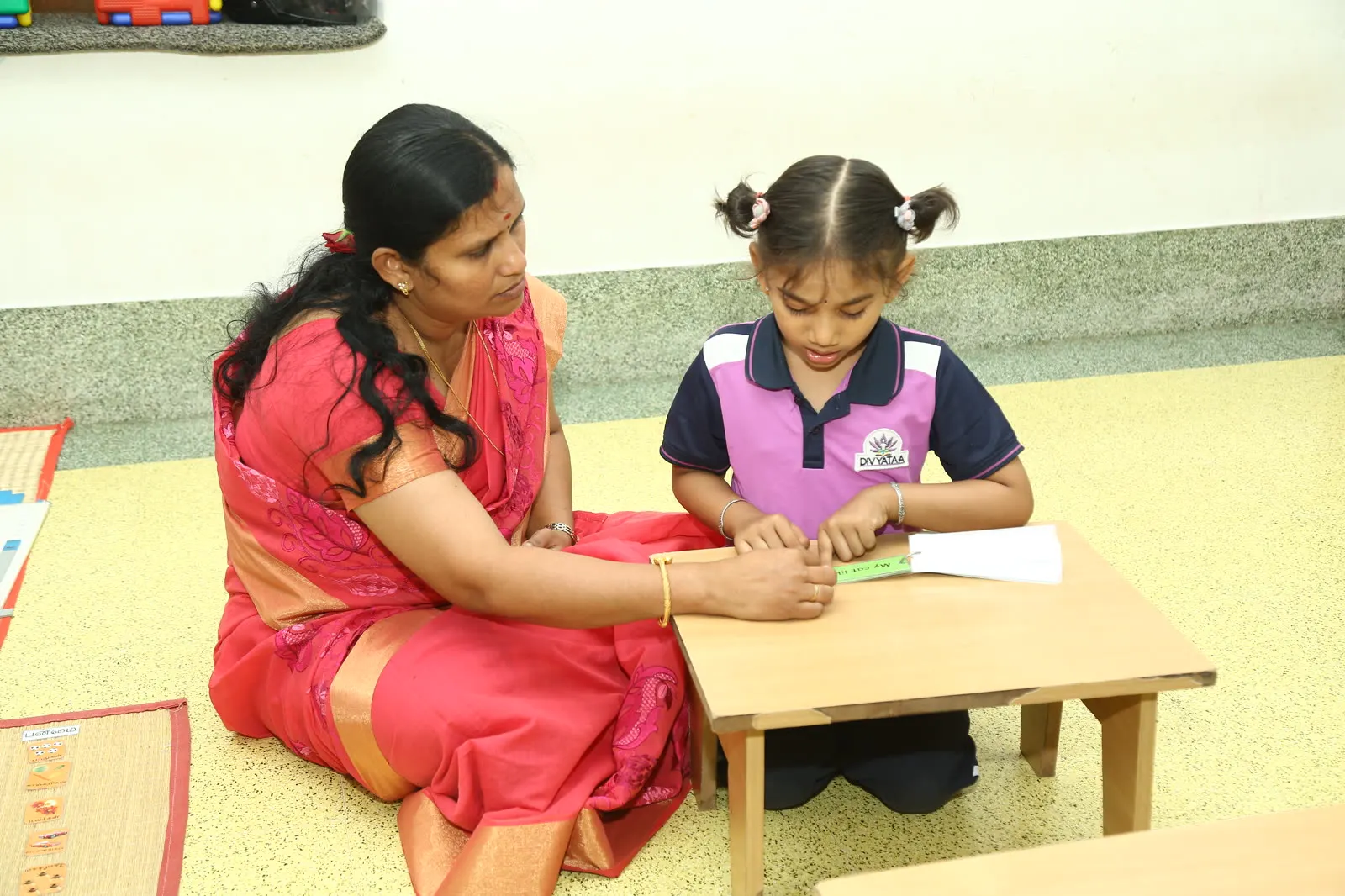 A guide giving a child an individual lesson at a low work table