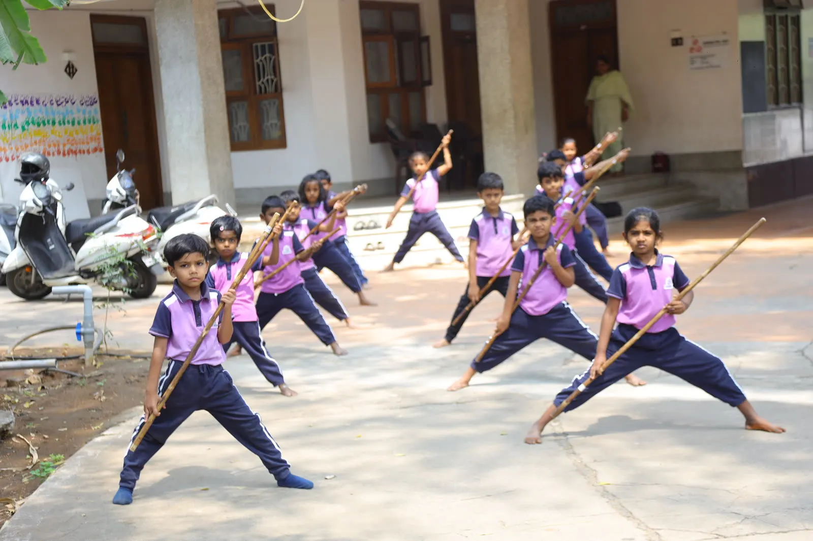 Children practising silambam, the traditional Tamil stick art, in the school courtyard