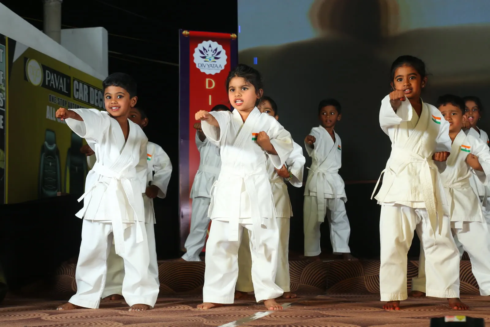 Children in karate uniforms performing a kata on stage