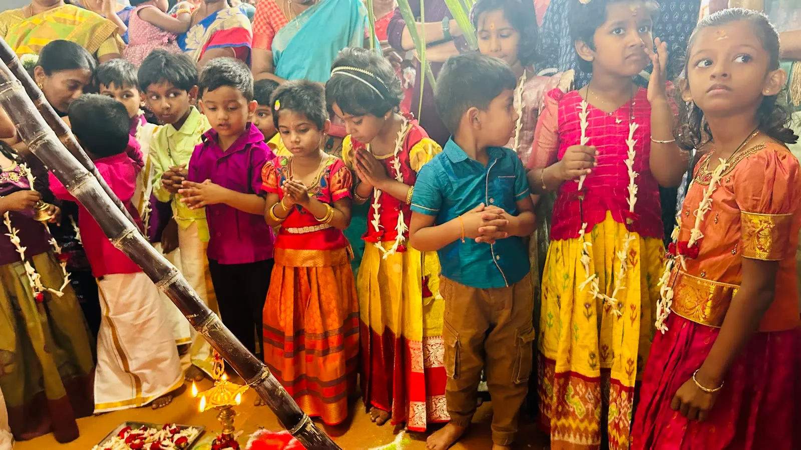 Children in traditional clothes celebrating Pongal with sugarcane