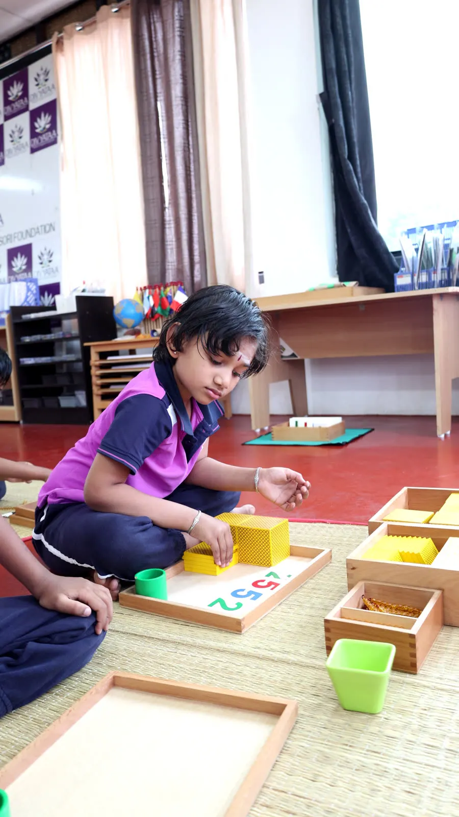 A child building numbers with the Montessori golden bead material