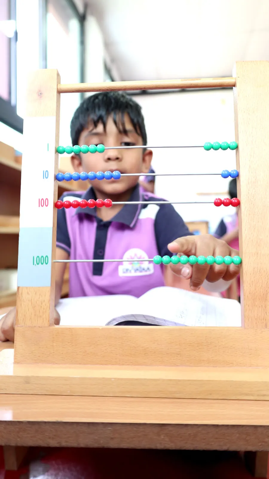 A child counting units, tens, hundreds and thousands on a bead frame abacus